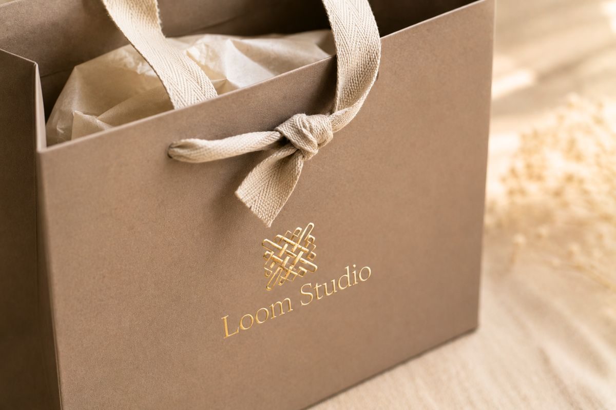 Taupe paper bag with cotton ribbon handle and gold foil logo